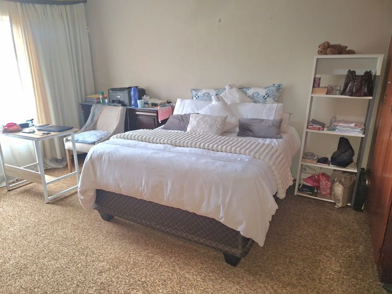 A bedroom featuring carpeted flooring and a built-in cupboard, offering a functional space that could benefit from modern updates.