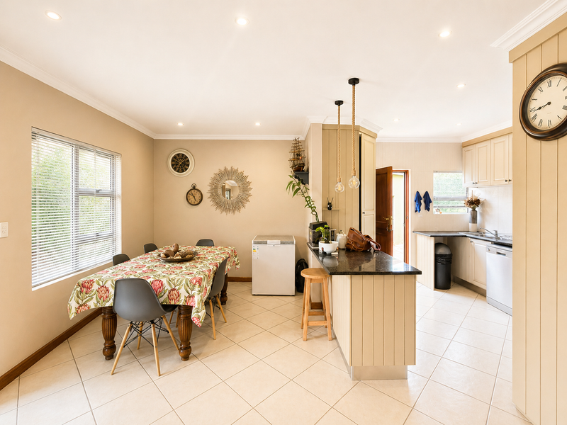 Open-plan kitchen and dining area featuring tiled flooring, granite countertops, built-in cabinetry, and recessed lighting, creating a functional and connected living space.