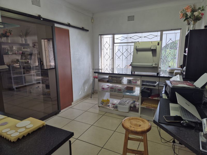 A functional utility or workspace featuring tiled flooring, built-in shelving units, and security bars on the windows.