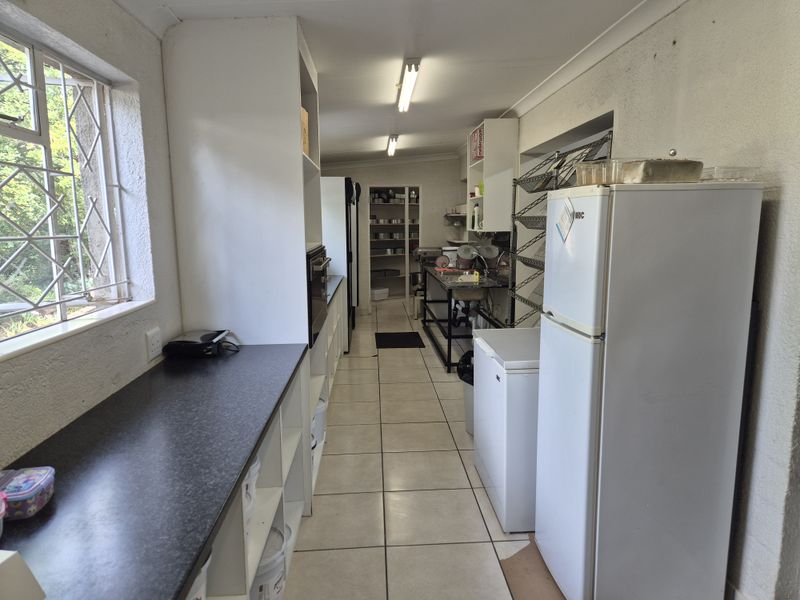 A functional scullery or utility prep area featuring tiled floors, built-in cabinetry, laminate countertops, and a stainless steel sink, requiring cosmetic updates.