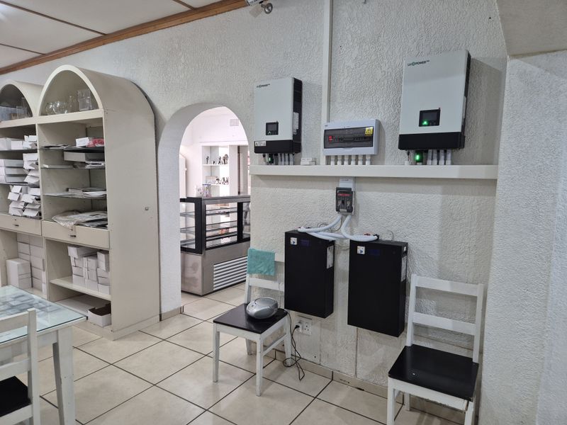 Utility area featuring a solar power installation with dual inverters and battery storage units, complemented by built-in shelving and tiled flooring.