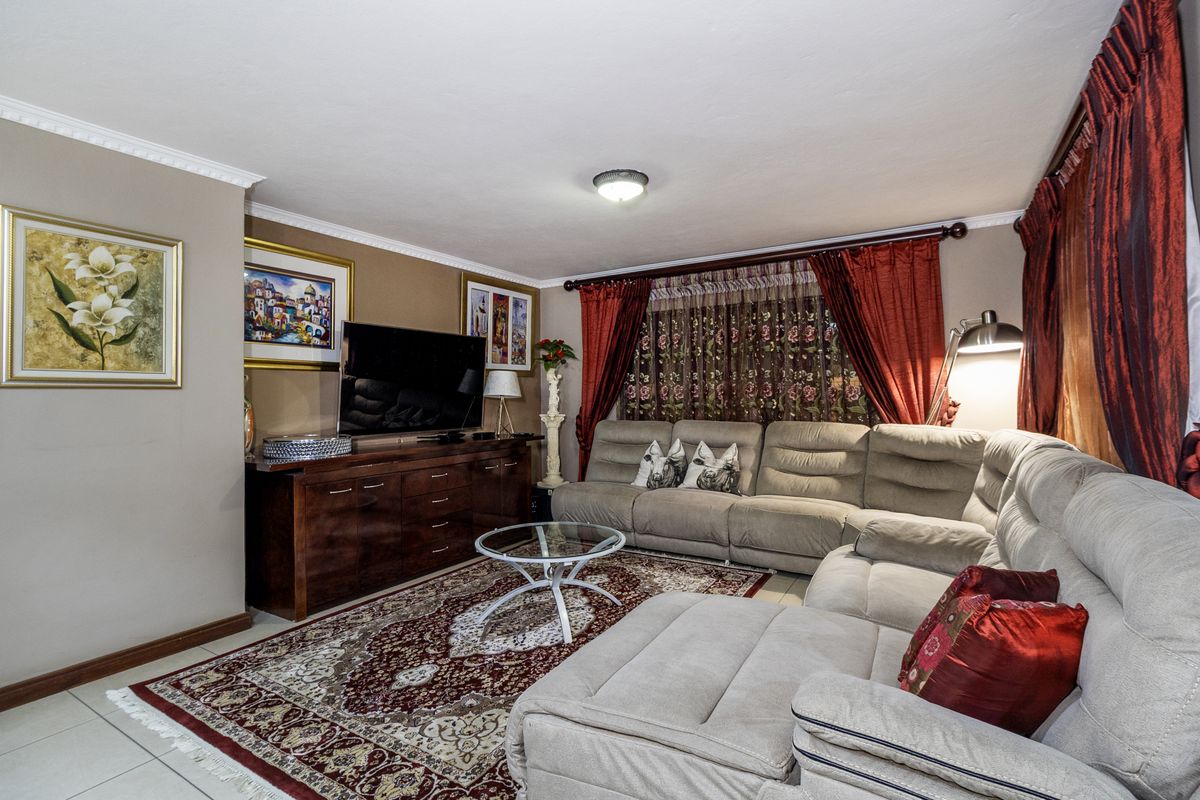 A comfortable living room featuring tiled flooring, crown molding, and a neutral wall finish, providing a functional space for relaxation.