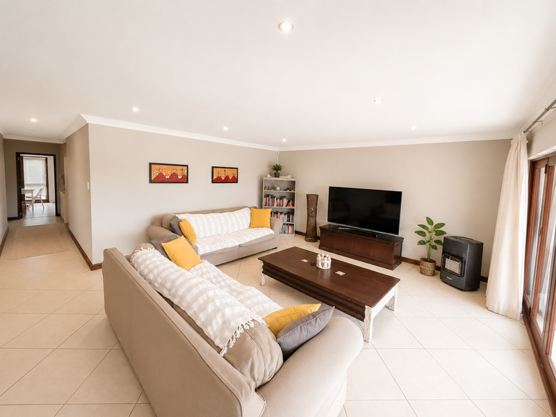 Spacious living room featuring neutral tiled flooring, recessed downlighting, and large sliding glass doors providing access to the outdoor area.
