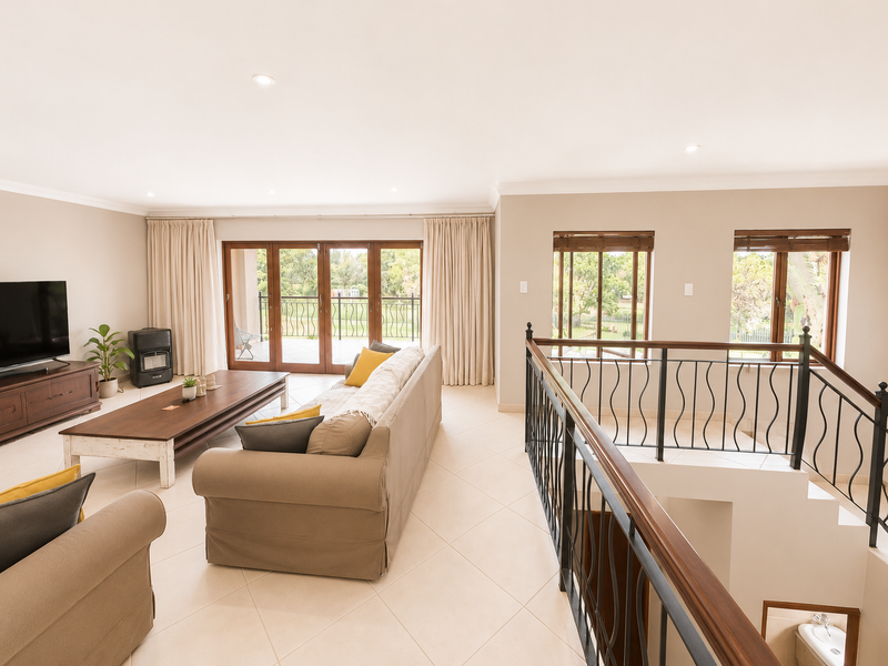 Spacious living area featuring tiled floors, recessed lighting, and a wrought iron staircase railing, with direct access to an outdoor balcony through sliding glass doors.