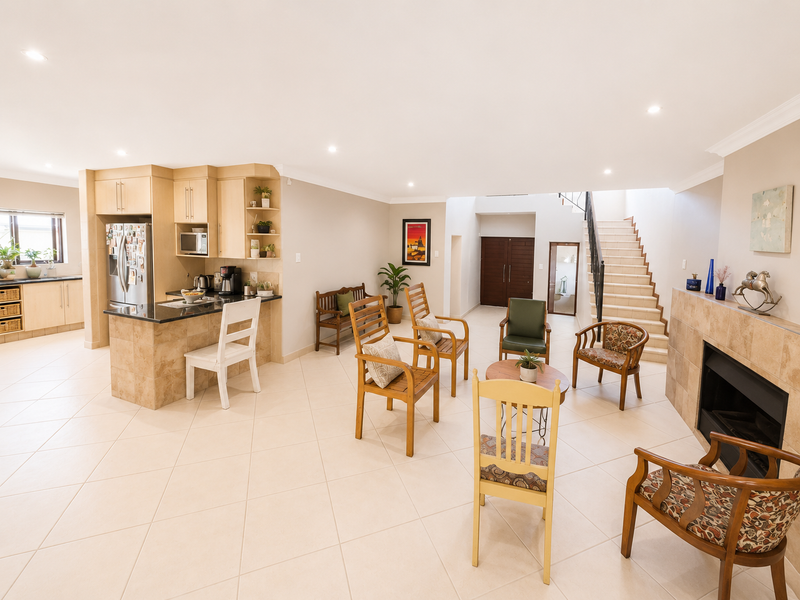 Spacious open-plan living area featuring a modern kitchen with granite countertops, a built-in fireplace, and a staircase leading to the upper level.