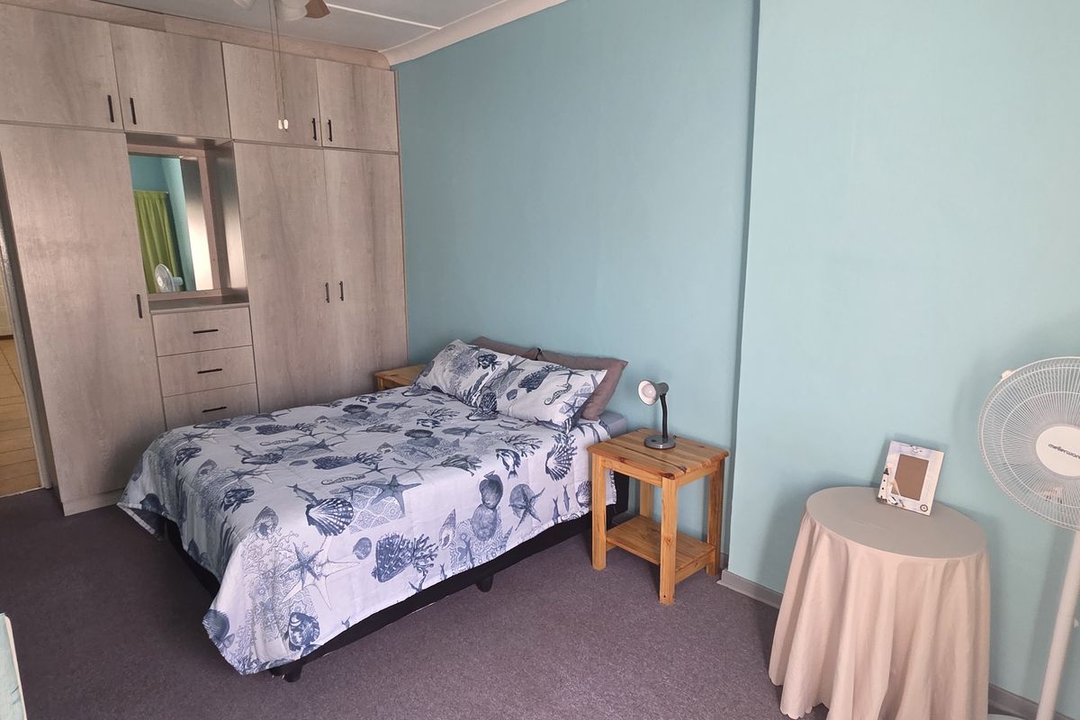 A bedroom featuring built-in cupboards with integrated shelving and carpeted flooring, offering functional storage space.