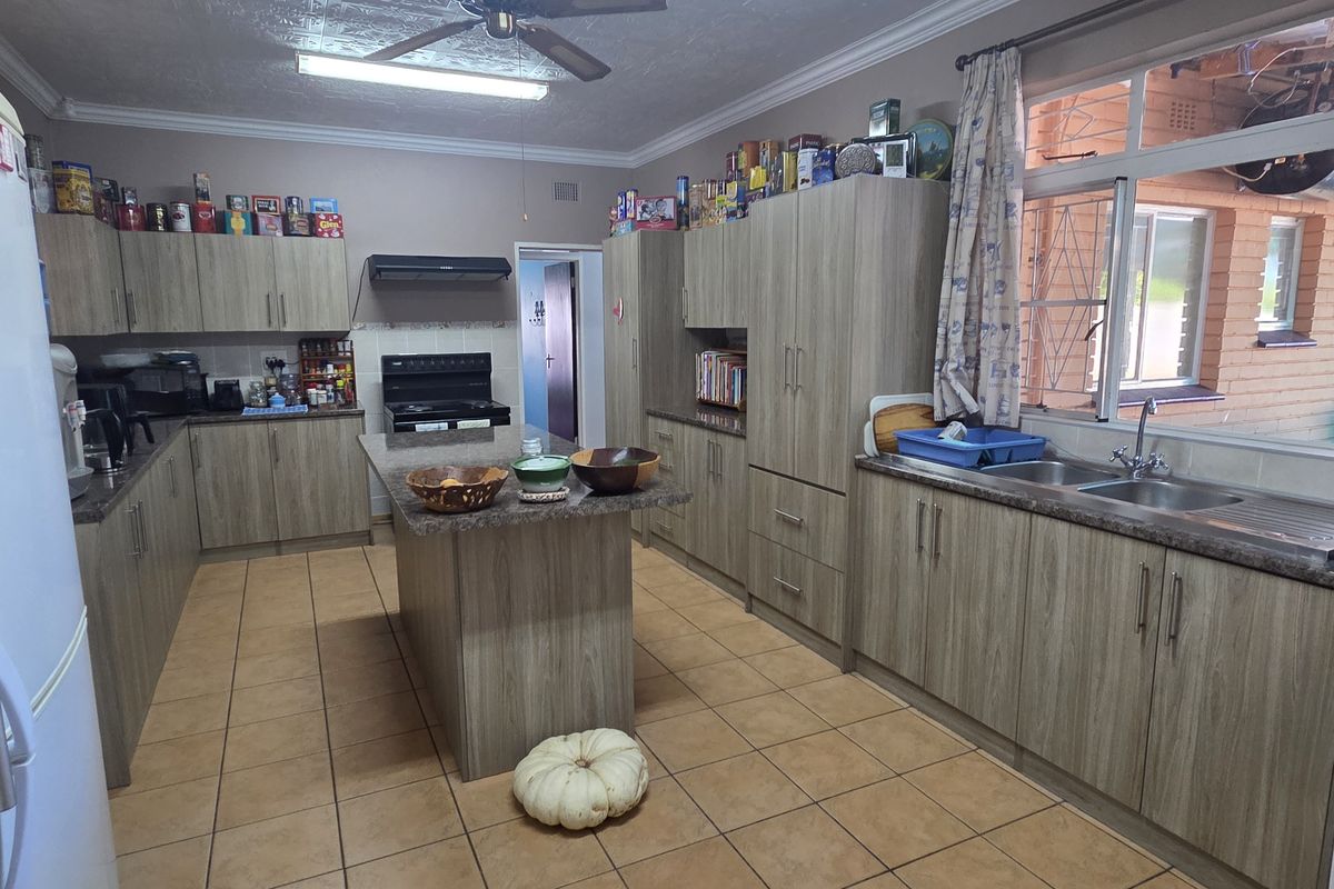 Spacious kitchen featuring wood-look cabinetry, a central island, tiled flooring, and a double sink with views to the exterior.