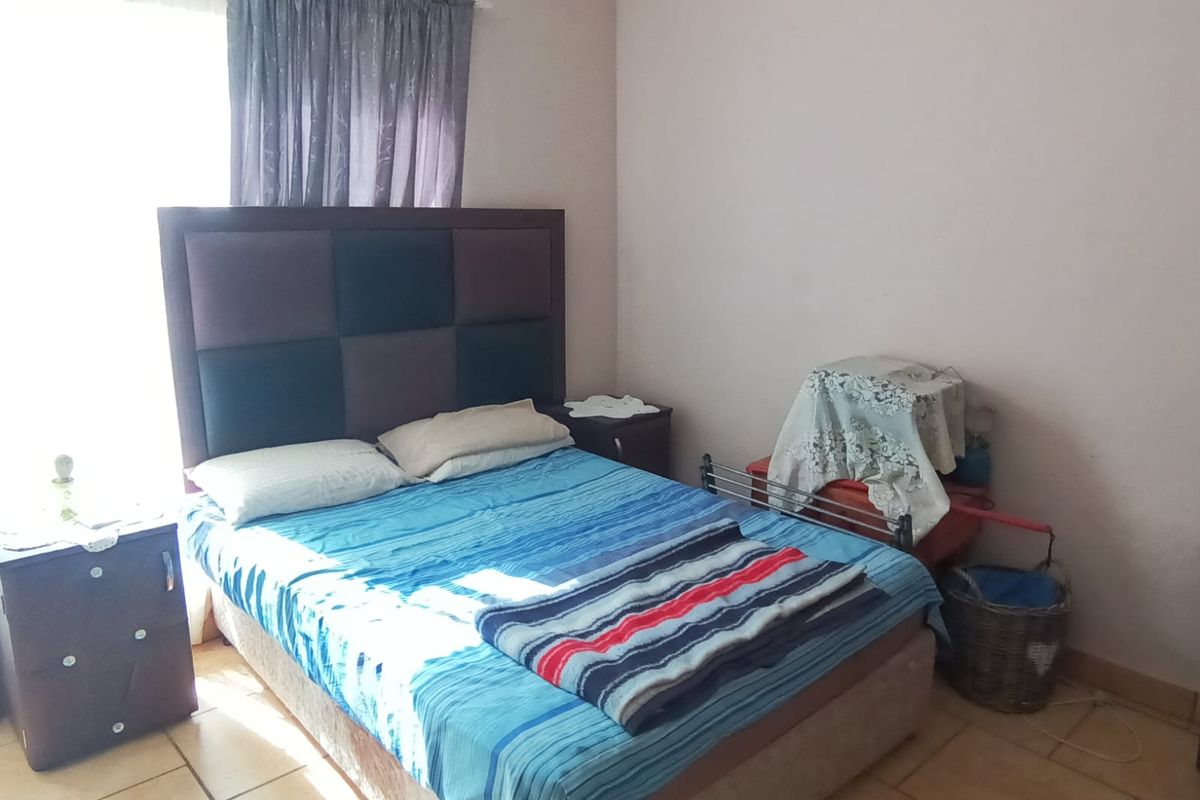 A standard bedroom featuring tiled flooring and natural light from a window.