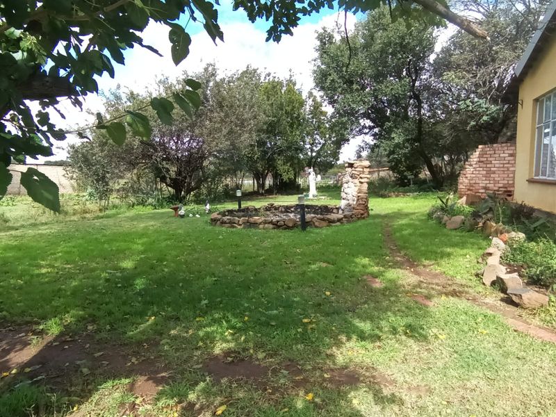 A spacious garden area featuring a stone-clad water feature, mature trees, and established lawn, providing a natural outdoor setting for the property.