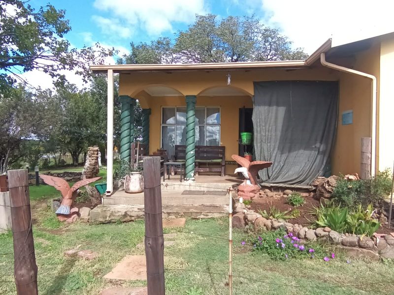 A covered patio area featuring decorative columns and concrete flooring, providing an outdoor space overlooking the garden.