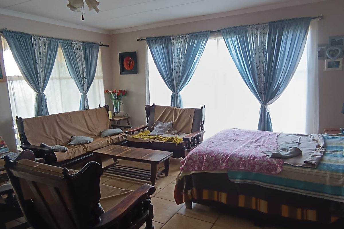 A spacious living area featuring tiled flooring, a ceiling fan, and large sliding glass doors that provide ample natural light.