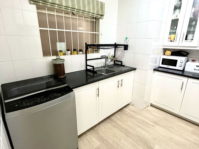 A clean, functional kitchen featuring white cabinetry, black granite countertops, stainless steel sink, and light wood-look laminate flooring.