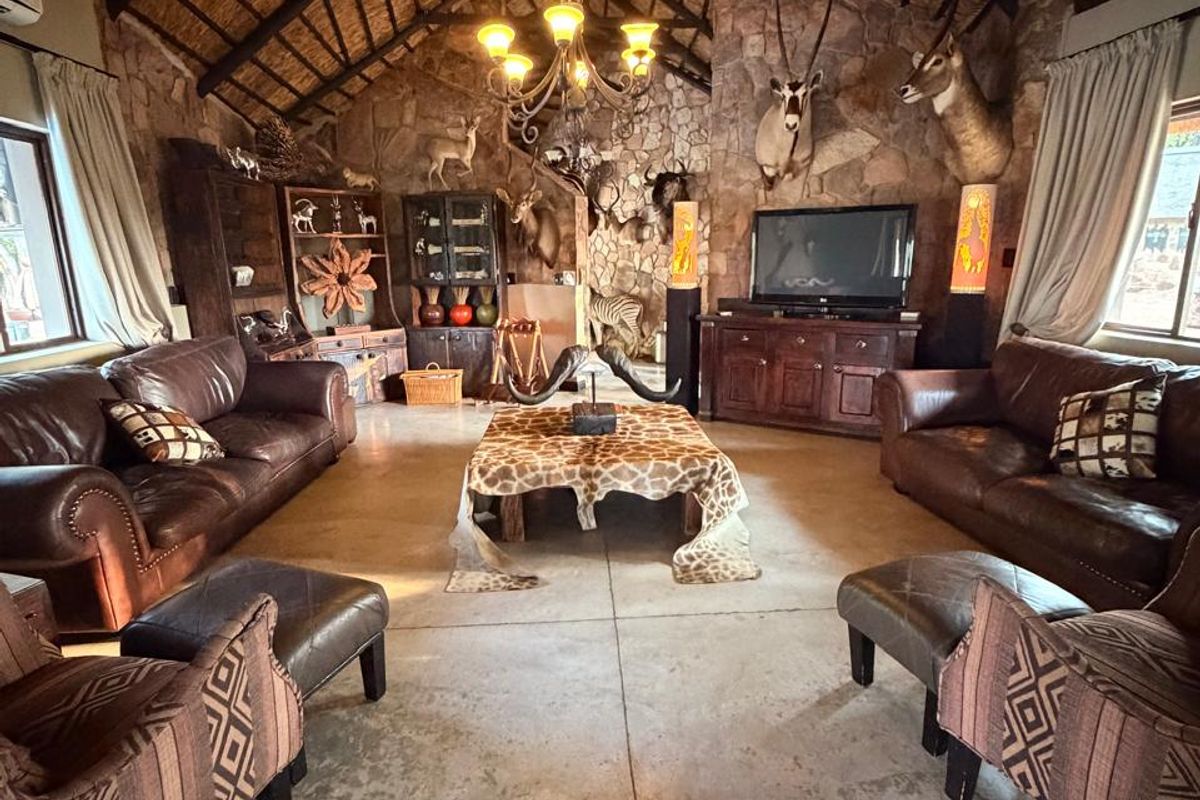 Spacious living room featuring a high vaulted thatched ceiling with exposed timber trusses, stone feature wall, and polished concrete flooring.