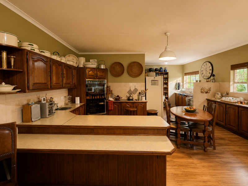 Spacious open-plan kitchen and dining area featuring traditional wooden cabinetry, laminate countertops, and integrated appliances, offering a warm and functional layout.