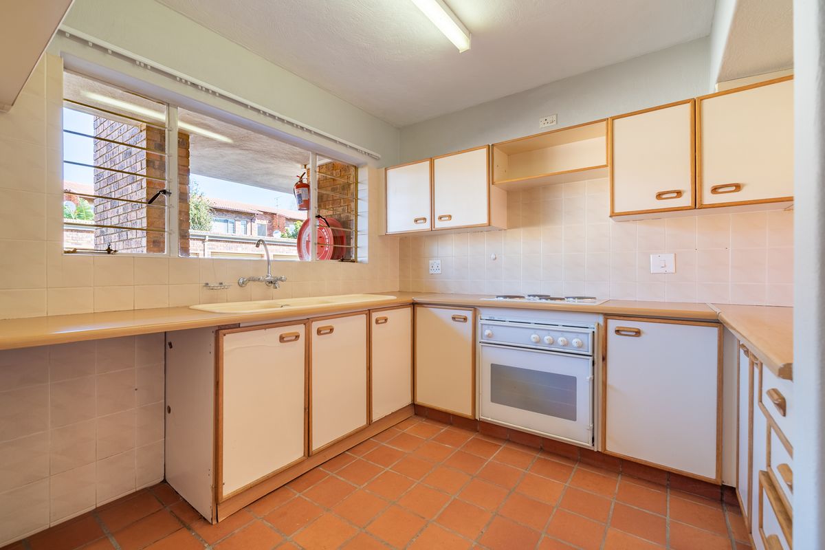A functional kitchen featuring built-in cabinetry, laminate countertops, a built-in oven with hob, and terracotta floor tiles, offering potential for modernization.