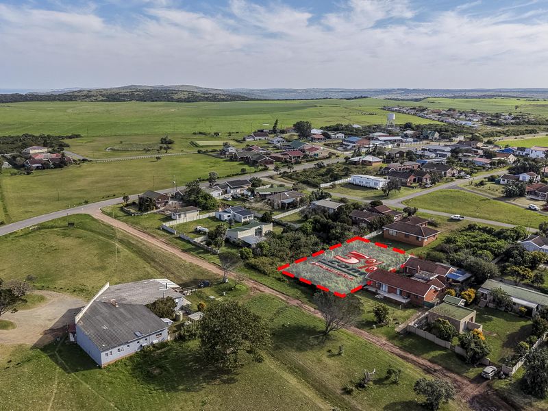 An aerial view of a residential vacant land plot highlighted in red, situated within a coastal neighborhood setting.
