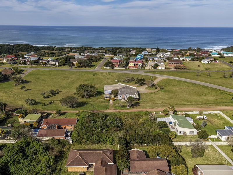 Aerial view of a coastal residential neighborhood featuring vacant land plots, established homes, and proximity to the ocean.