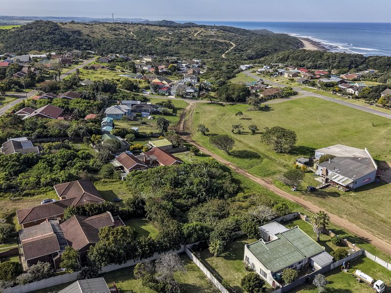 Aerial view of a coastal residential neighborhood featuring open land, established housing, and proximity to the ocean.