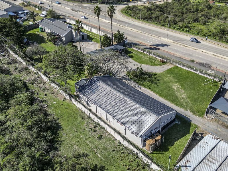 Aerial view of the property showing the main building with a metal roof, perimeter wall, water tanks, and shade cloth carports.