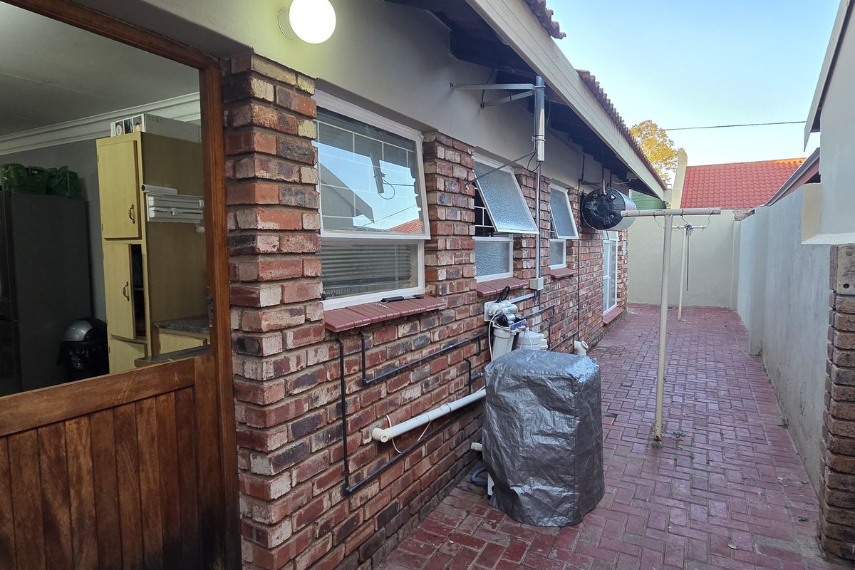 Rear exterior view of the townhouse featuring brick paving, a stable door entrance, and external utility fixtures including a water filtration system.