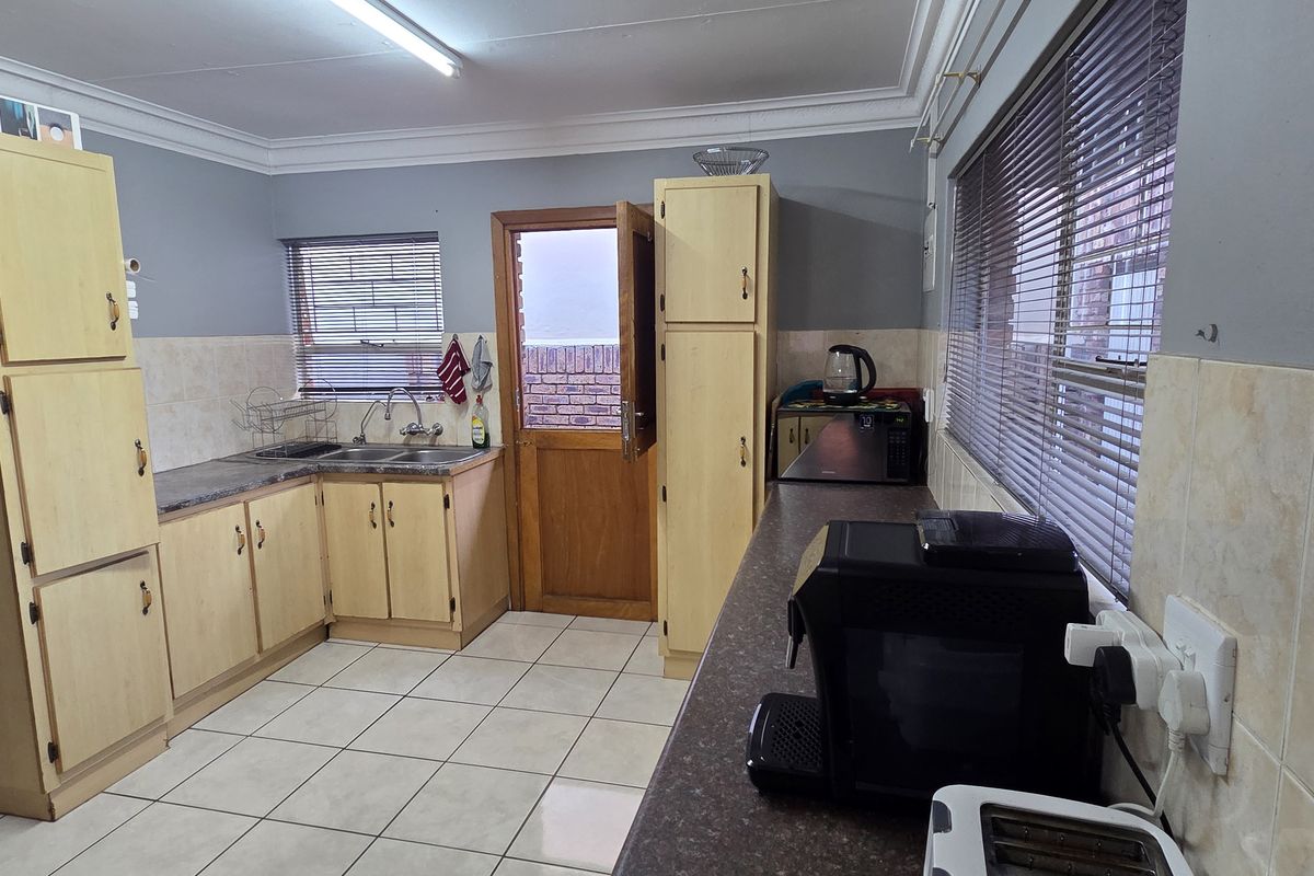 Functional kitchen featuring laminate cabinetry, tiled flooring, and direct access to the exterior, offering a practical layout with potential for modern updates.