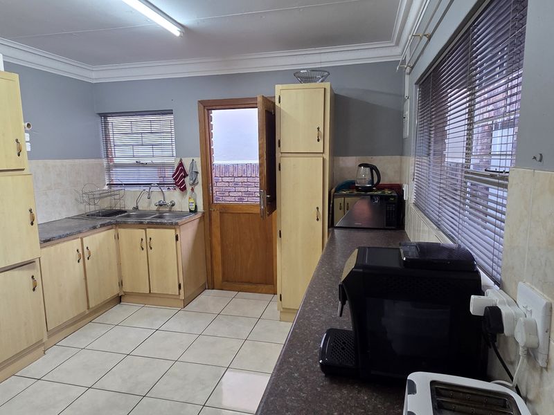 Functional kitchen featuring laminate cabinetry, tiled flooring, and direct access to the exterior, offering a practical layout with potential for modern updates.