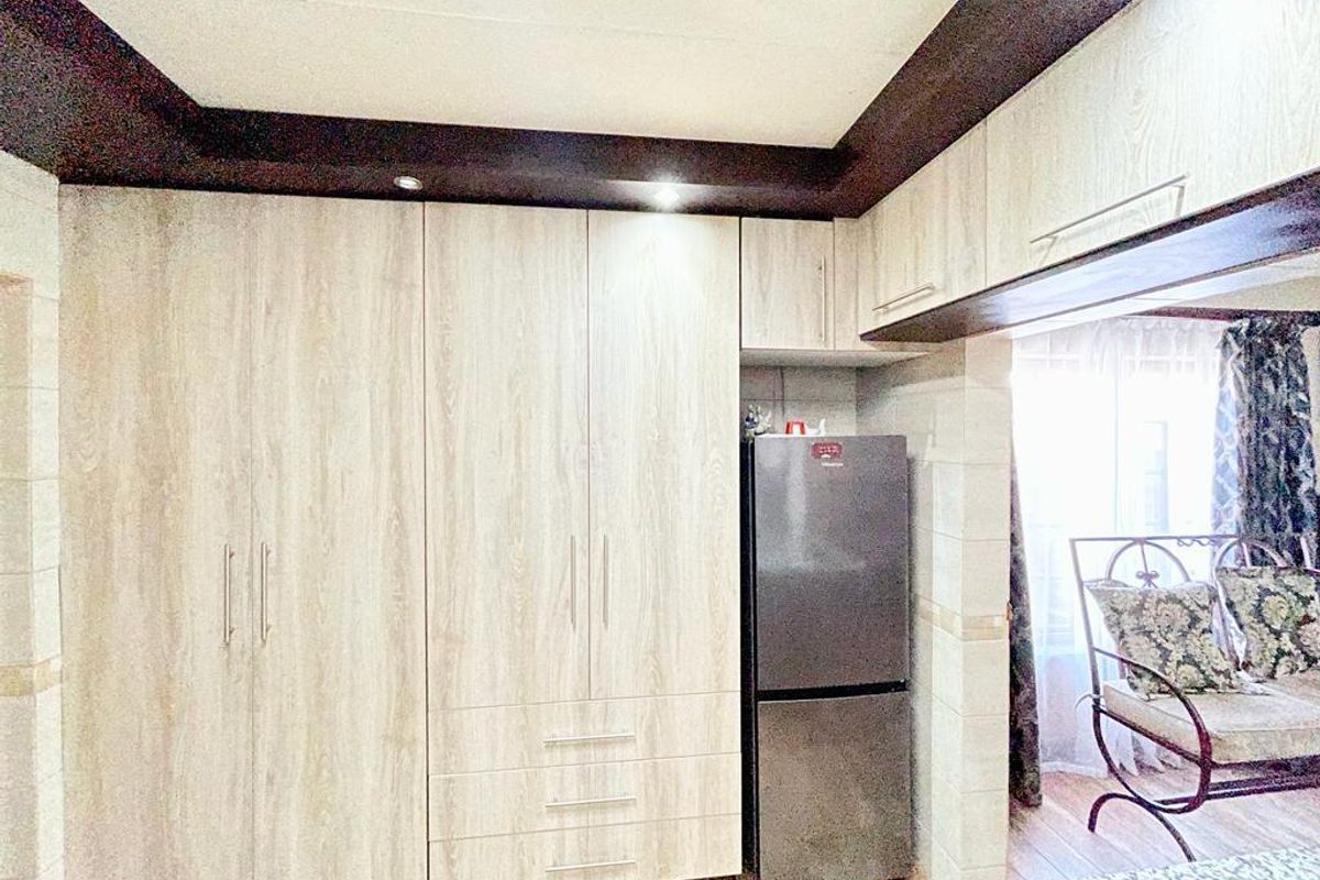 A bedroom featuring extensive built-in cabinetry with light wood-grain finish, dark ceiling trim, and recessed lighting.