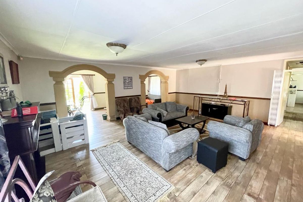 Spacious living area featuring decorative arched doorways, wood-look flooring, and neutral wall tones, providing a versatile layout for comfortable family living.
