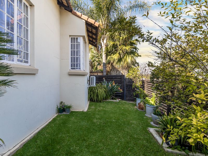 A private rear garden area featuring a well-maintained lawn, established perimeter fencing, and exterior wall access with an integrated air conditioning unit.