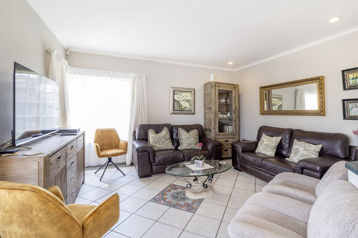 A comfortable living room featuring neutral tiled flooring and recessed downlighting, providing a functional and well-lit space for relaxation.