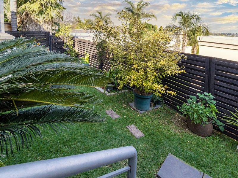 A private, well-maintained garden area featuring a lush lawn and modern timber slat perimeter fencing.