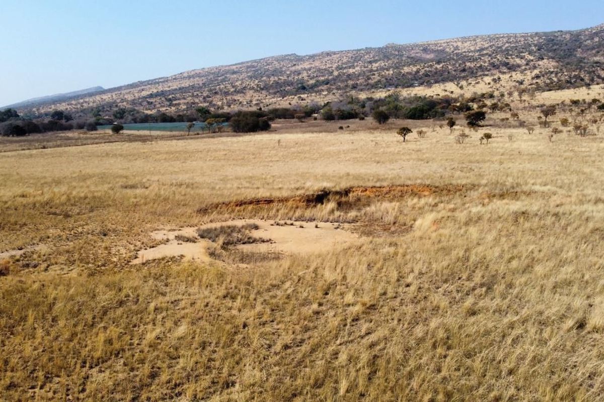 An aerial view of the expansive farm property featuring open grassland and visible natural soil erosion.