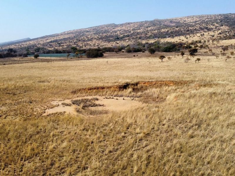 An aerial view of the expansive farm property featuring open grassland and visible natural soil erosion.