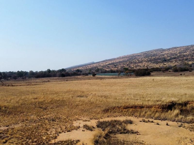 Expansive view of the farm property featuring open grassland and a scenic mountain backdrop.