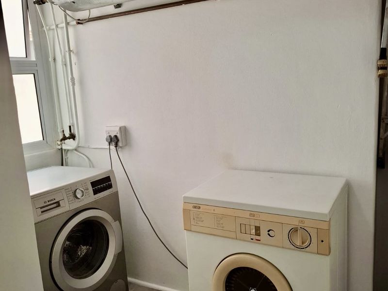 A functional laundry area featuring an overhead electric water heater and dedicated plumbing and electrical connections for laundry appliances.