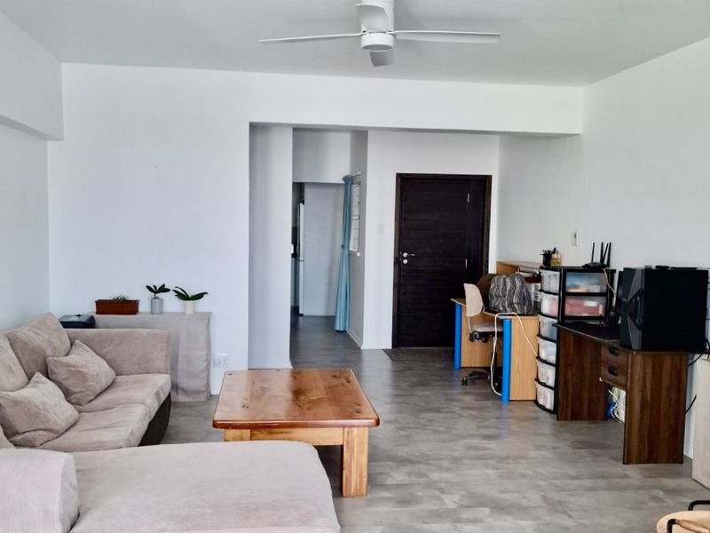 Open plan living area featuring neutral tiled flooring and a ceiling fan, providing a versatile space for relaxation and home office setup.