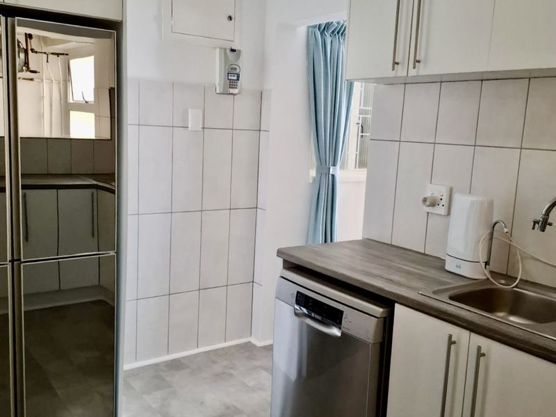 A functional kitchen featuring white cabinetry, tiled backsplash, and a stainless steel sink with a dedicated space for a dishwasher.