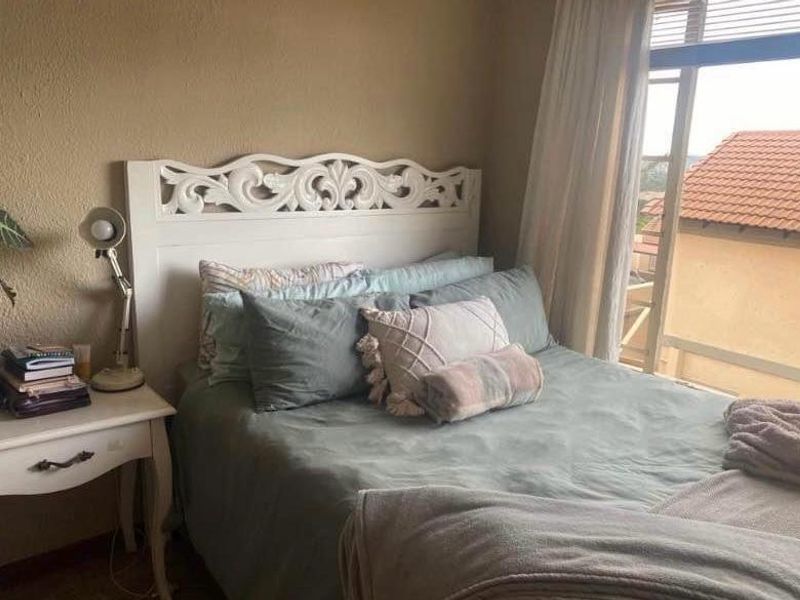 A cozy bedroom featuring a large window that allows for natural light and views of the surrounding townhouse complex.