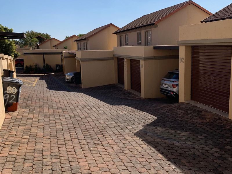 A view of the townhouse complex driveway featuring multiple garage entrances with roll-up doors and paved access.