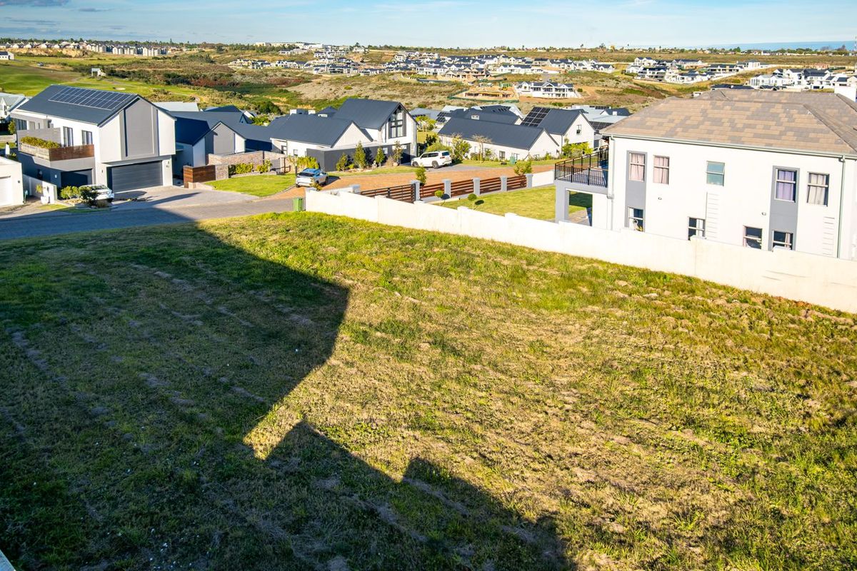 An elevated view of a vacant residential plot situated within a developed estate, featuring surrounding homes and clear boundary lines.