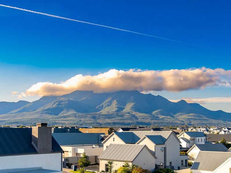 A scenic elevated view overlooking a residential neighborhood with a prominent mountain range in the background under a clear blue sky.