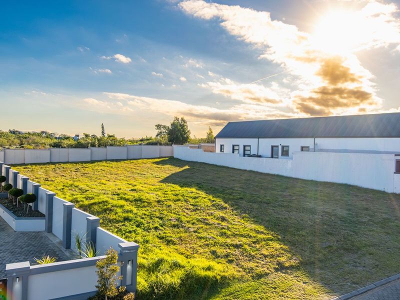 A spacious, level residential vacant plot featuring a paved driveway, perimeter walling, and established garden borders, ready for development.