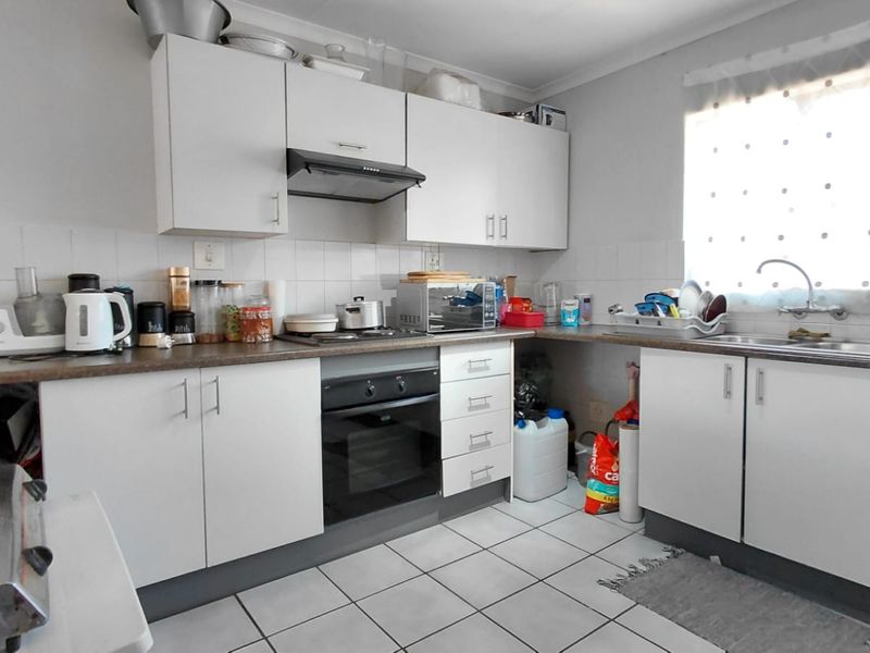 Functional kitchen featuring white cabinetry, laminate countertops, built-in oven, extractor fan, and tiled flooring with a practical layout.