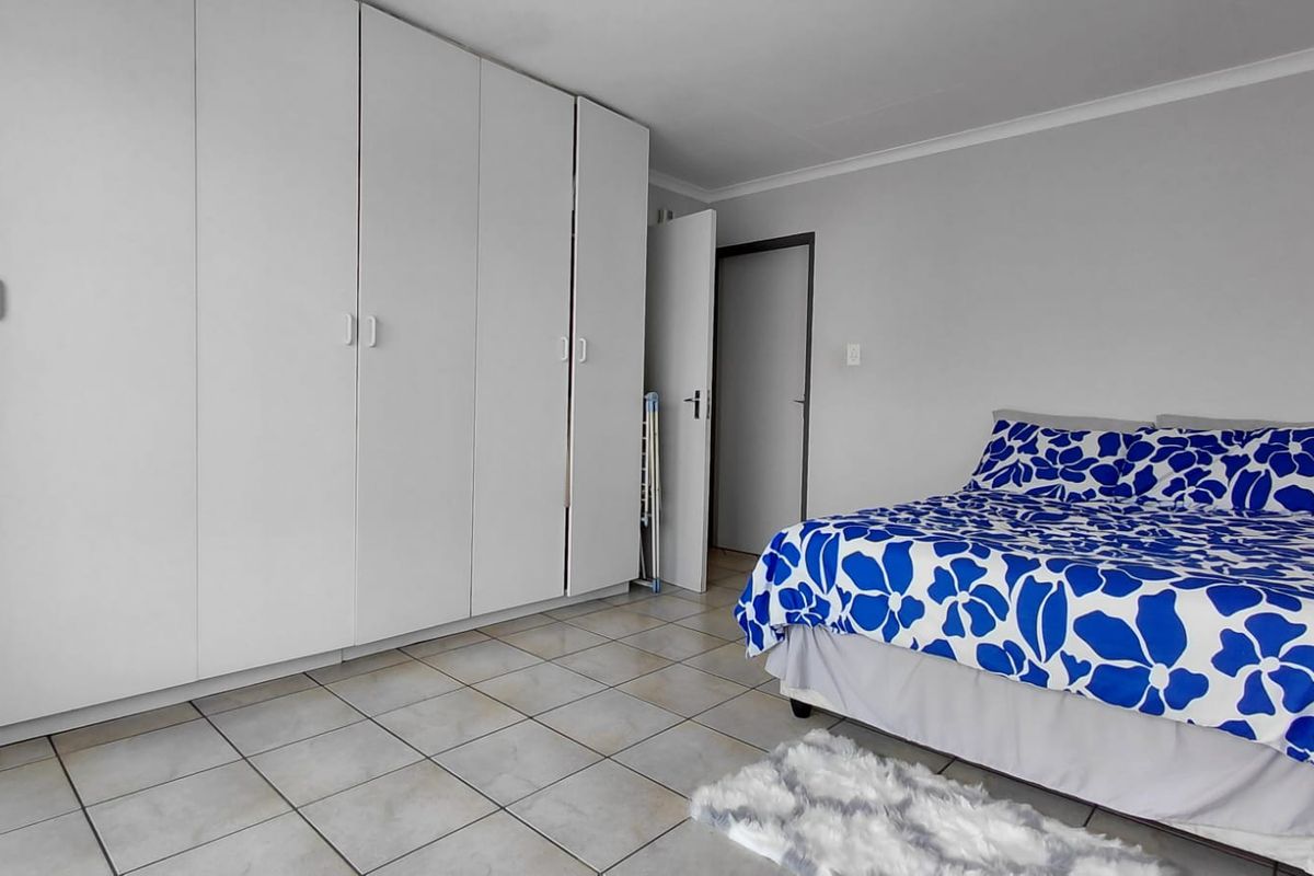 A bedroom featuring neutral tiled flooring and extensive white built-in cupboards providing ample storage space.