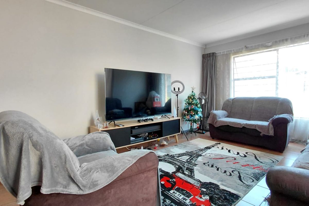 A comfortable living room featuring tiled flooring and a large window that allows for natural light.