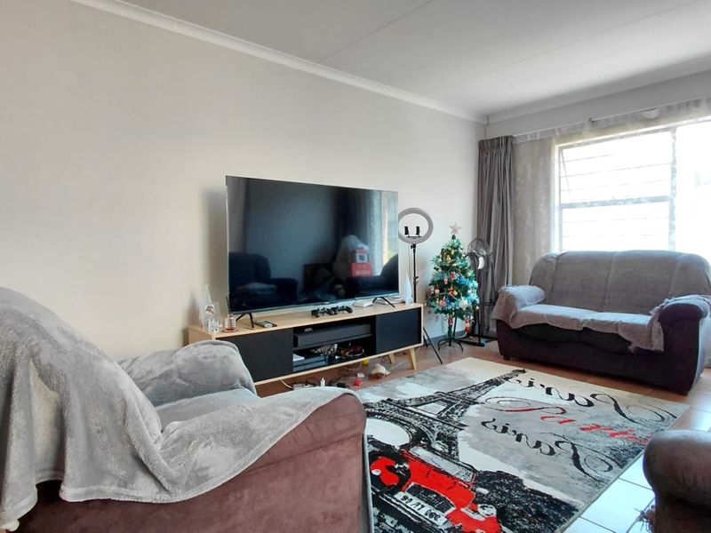 A comfortable living room featuring tiled flooring and a large window that allows for natural light.