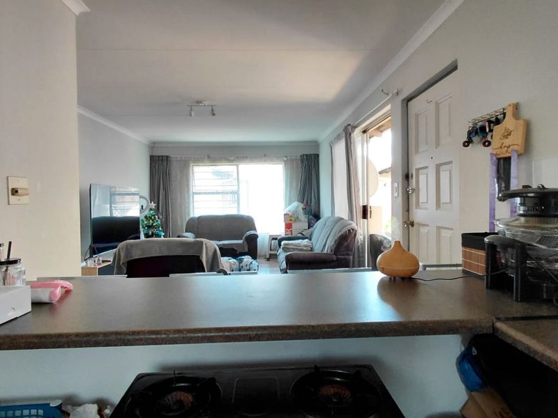 Open plan living area featuring a kitchen breakfast bar overlooking the lounge with access to an outdoor patio area.