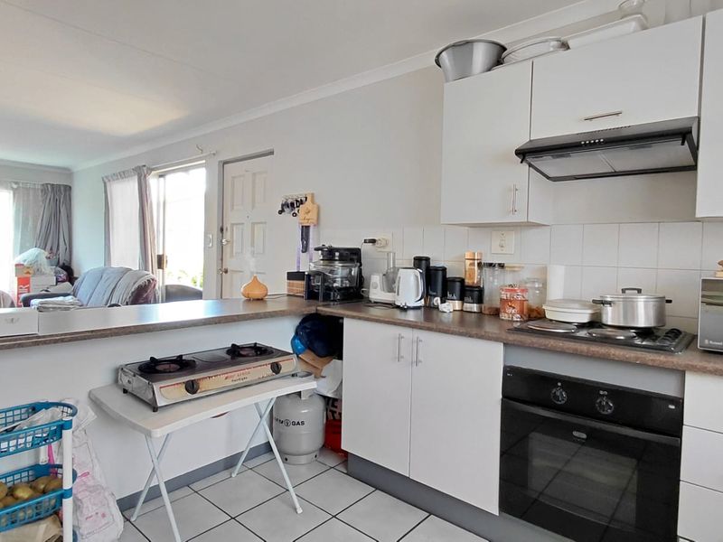 Open-plan kitchen featuring built-in cabinetry, oven, extractor fan, and tiled flooring, seamlessly connecting to the adjacent living area.