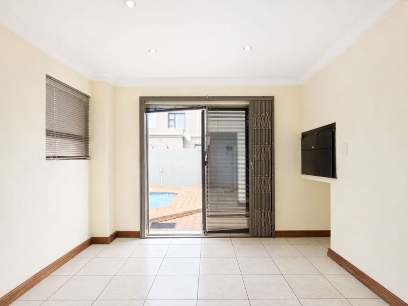 An empty living room featuring tiled floors, recessed lighting, and a built-in fireplace, with sliding door access to the outdoor pool area.