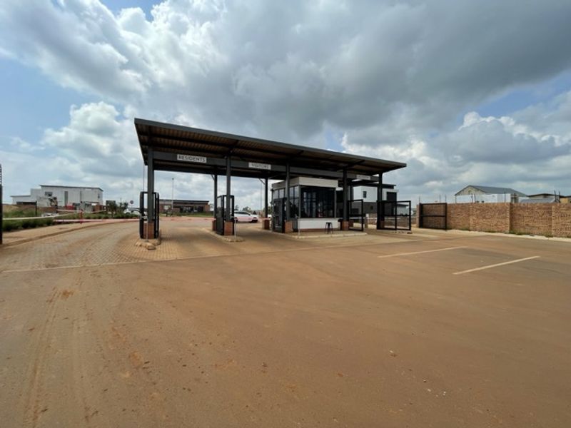 A modern security gatehouse and access control point featuring a covered driveway structure for residents and visitors.